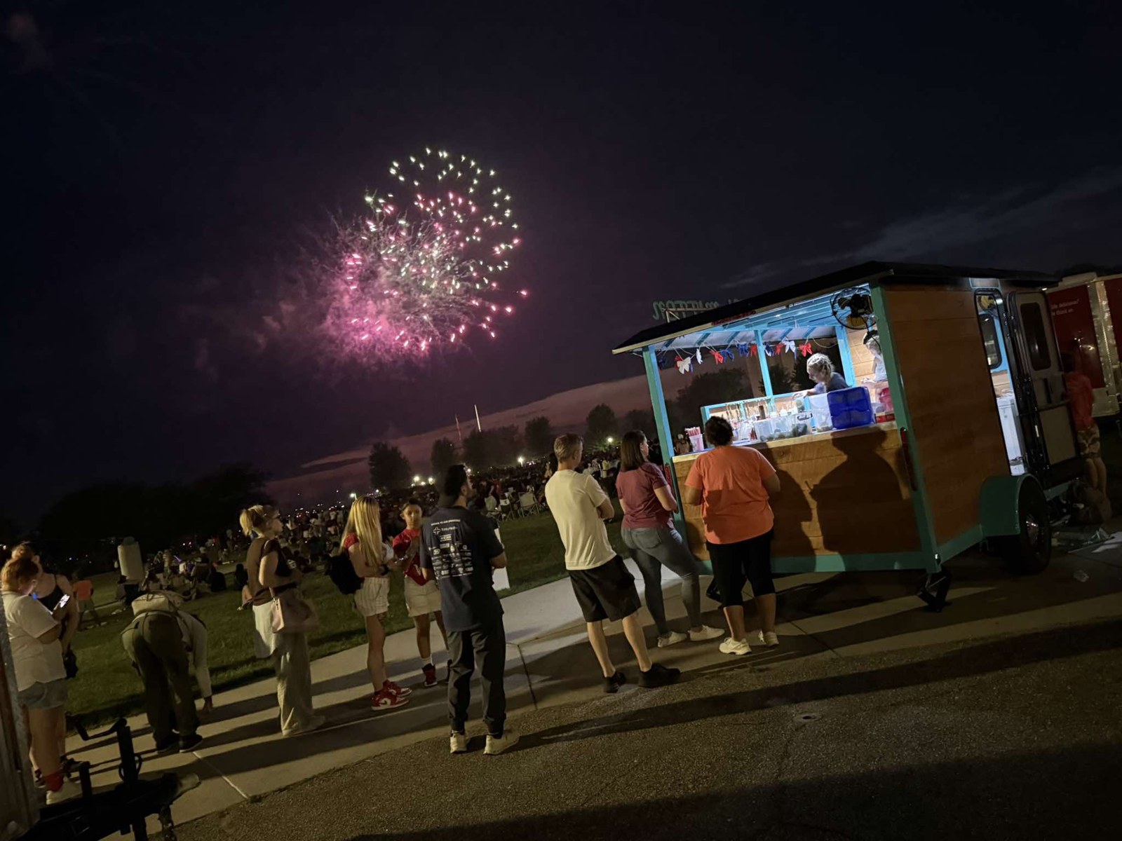 Guests gathered at The Thirsty Mitten trailer with fireworks overhead